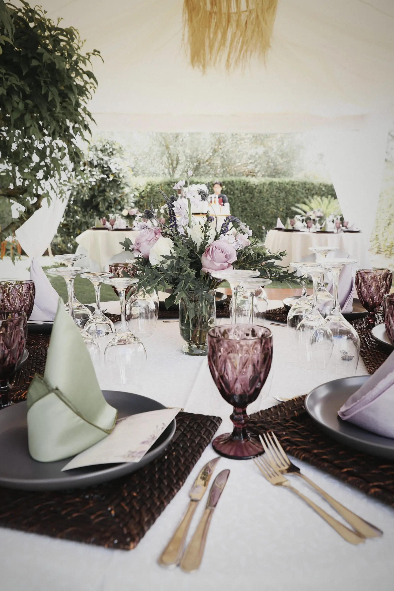 A place setting under the canopy: linen, glass, flowers and woven textures.