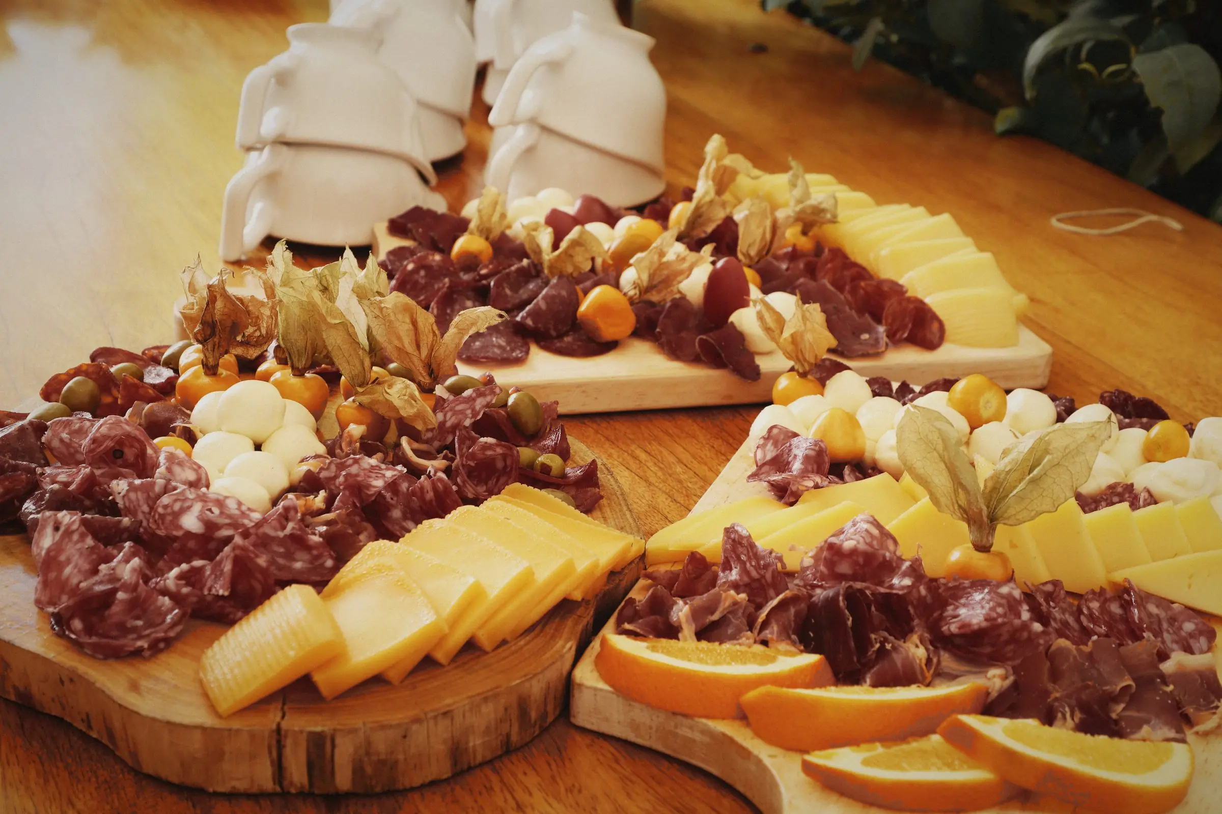 A grazing board of cured meats, cheeses and fruit on wood.