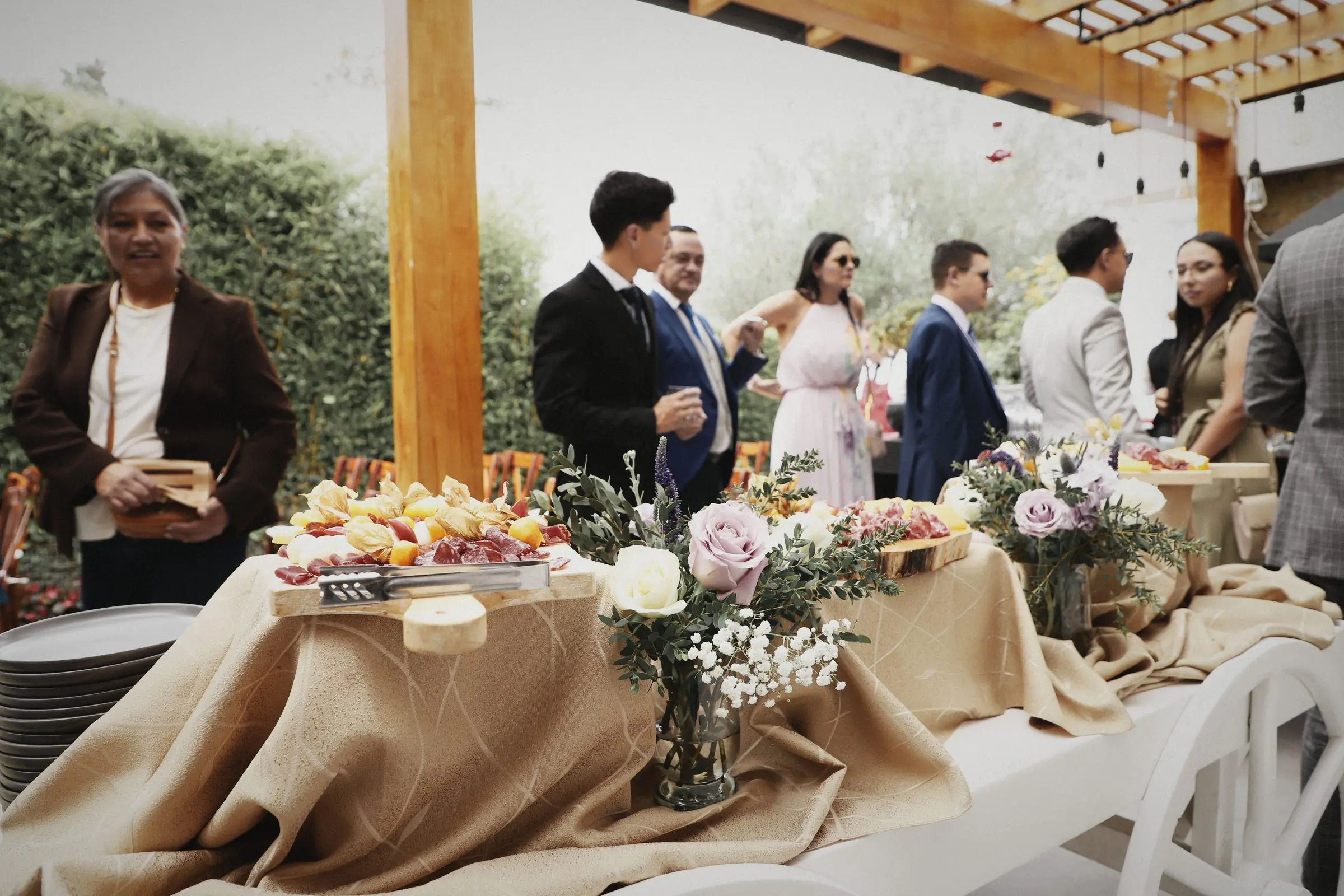 Guests gathering around a buffet table under a timber pergola.